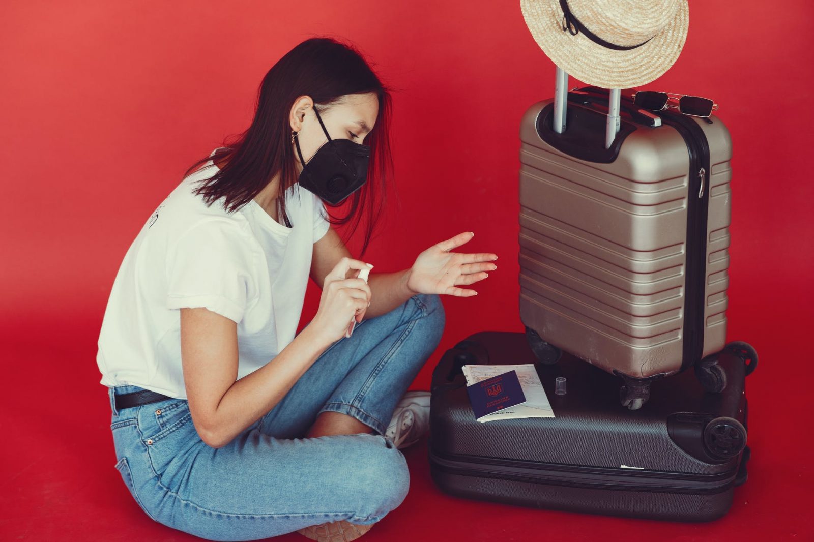 young traveler sanitizing hand on red background