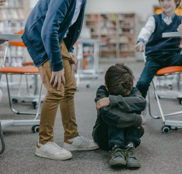 sad boy in gray sweater sitting on the floor