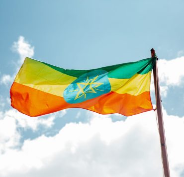 national colorful flag of ethiopia under cloudy sky