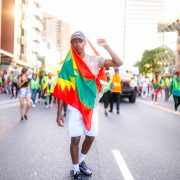 a man riding his skateboard with a flag tied around his body