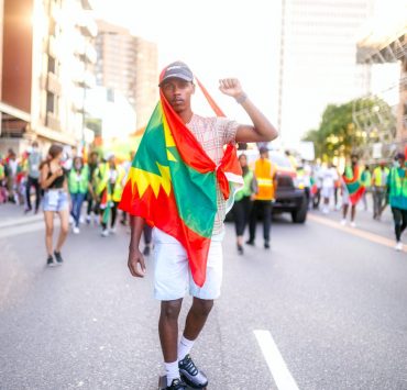 a man riding his skateboard with a flag tied around his body
