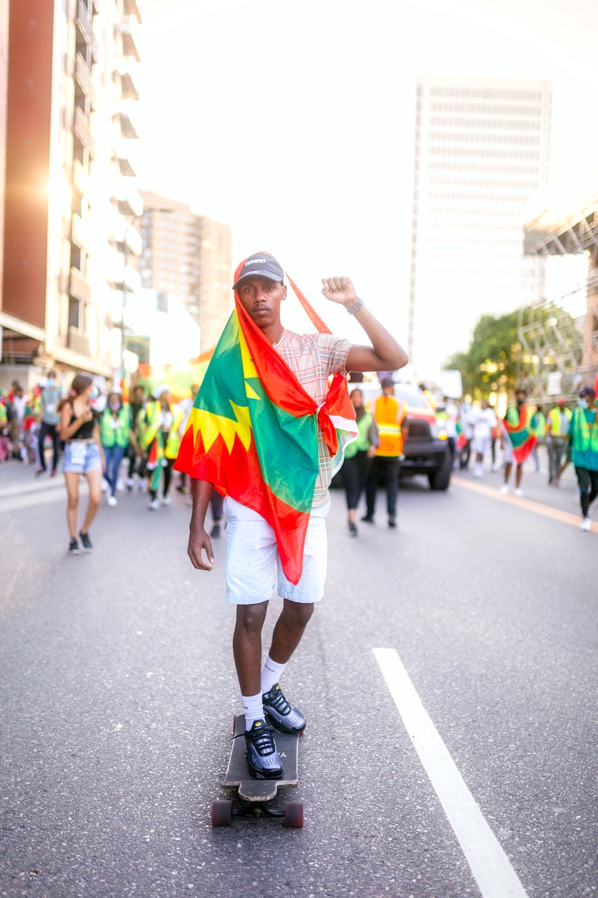 a man riding his skateboard with a flag tied around his body