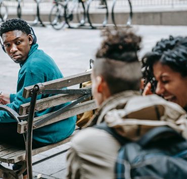 couple of students gossiping and laughing near black man