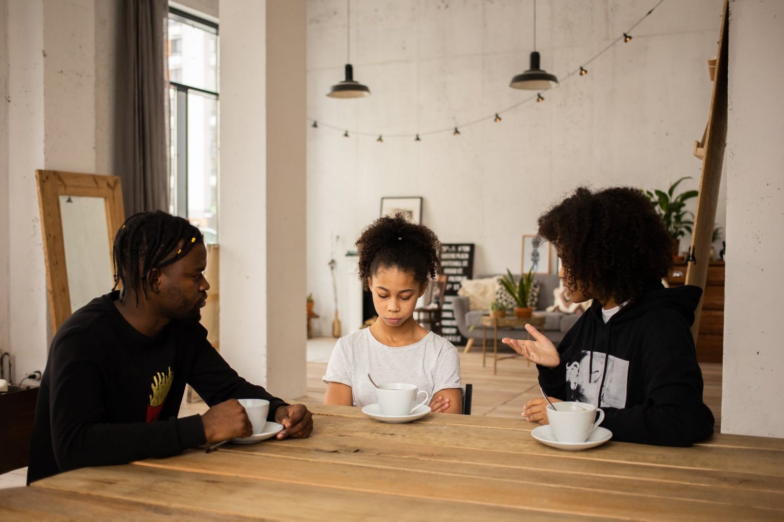 black parents lecturing upset daughter at table