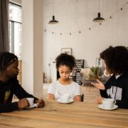 black parents lecturing upset daughter at table