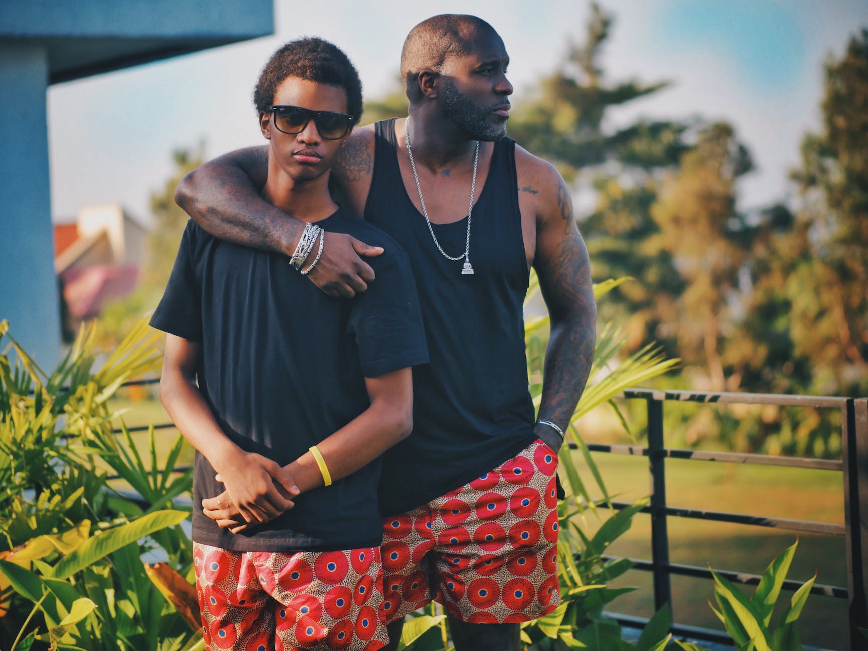 man putting his shoulder around boy while his other hand is inside his pocket