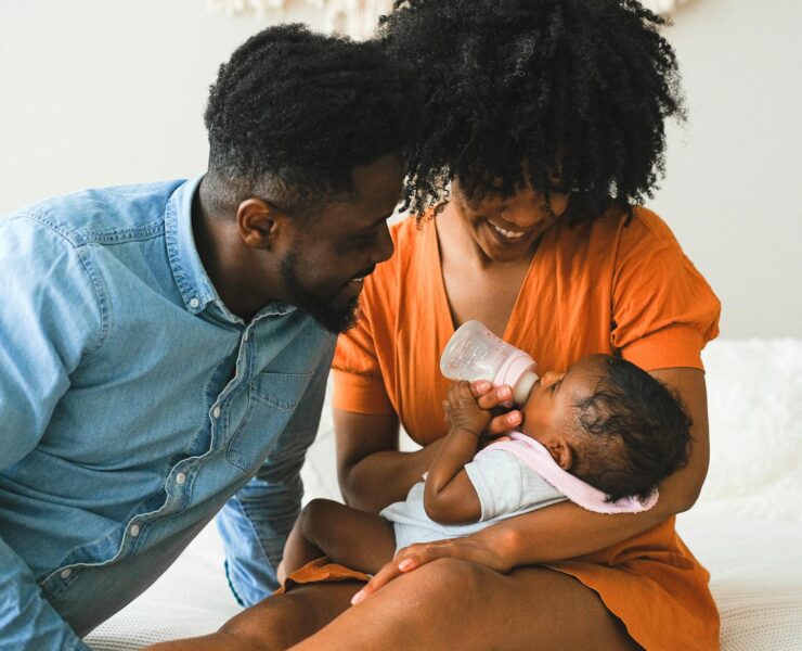 woman feeding a baby beside a man