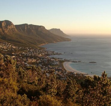 houses near shore surrounded by mountains
